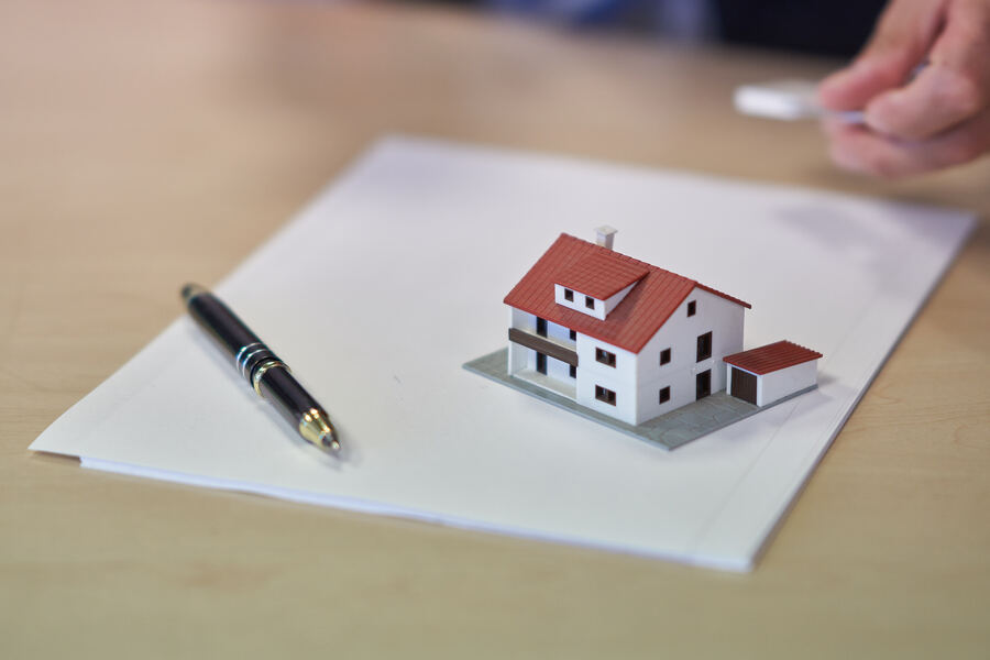 O que é ESG? Papel, caneta e miniatura de casa em destaque representando o contexto de ESG no mercado imobiliário